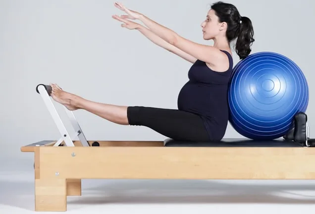 Exercício de Pilates em equipamento com bola de apoio